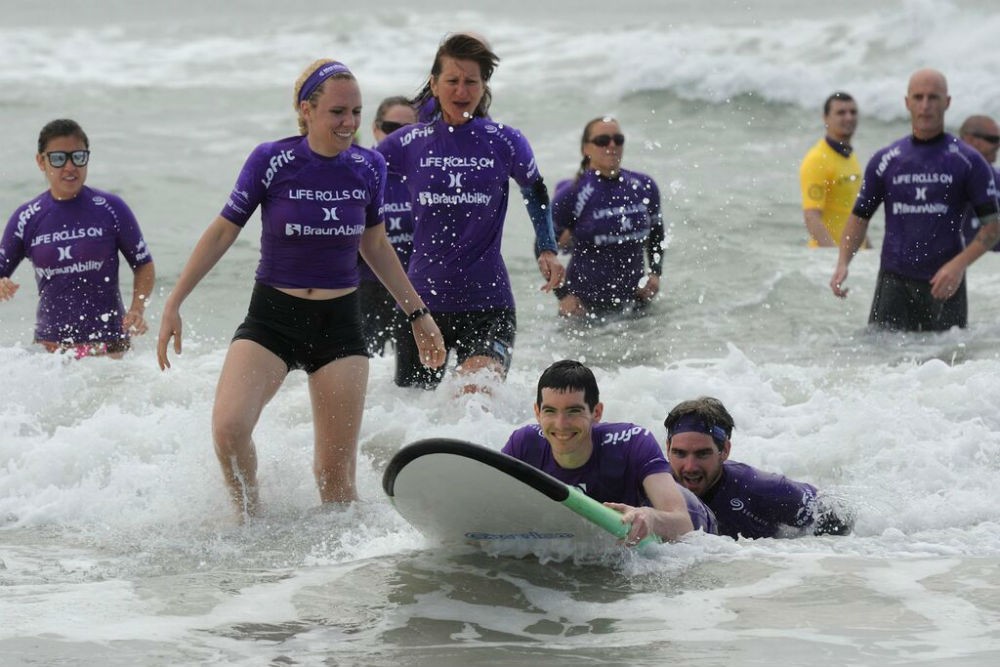 Volunteer surfers enabling paraplegics to surf as part of the nonprofit Life Rolls On program.