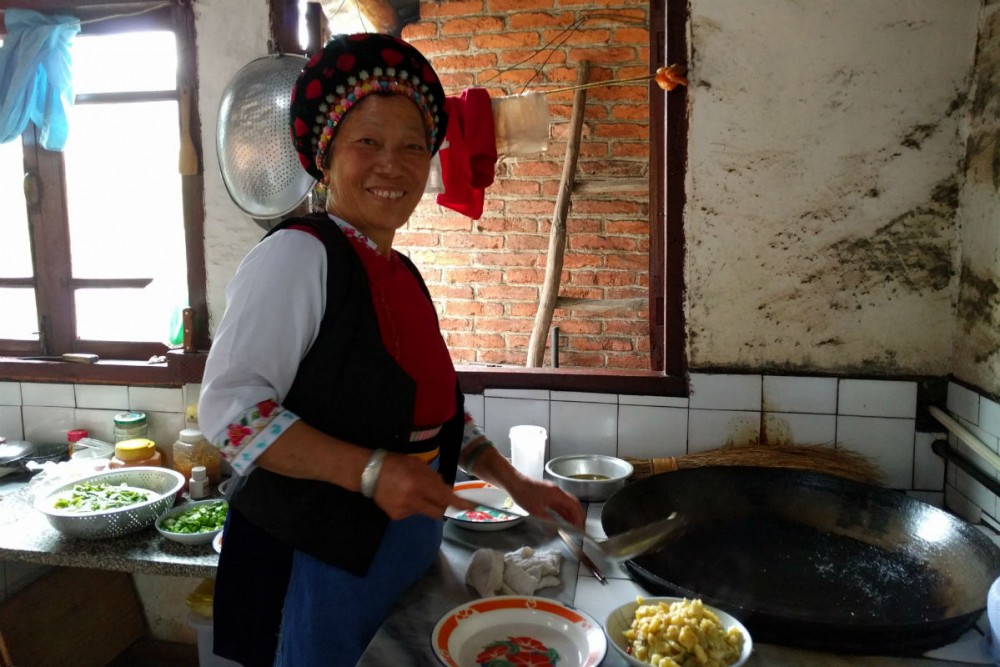 Bai minority woman cooking lunch in Yunnan Province China