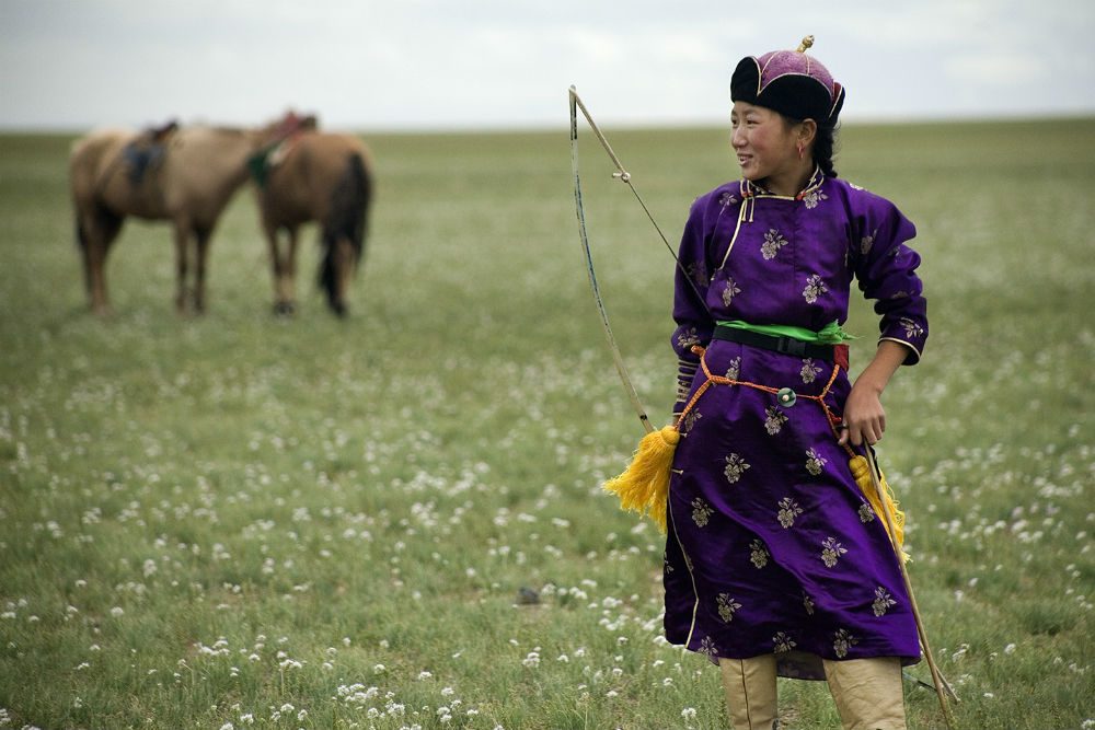 Naadam archer, standing in field with horse in Mongolia