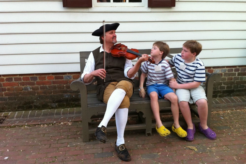 children listen to a historical reenactor play violin at Colonial Williamsburg Virginia