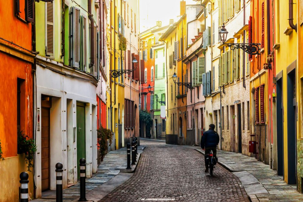 winding colorful street in Parma Italy with biker on it