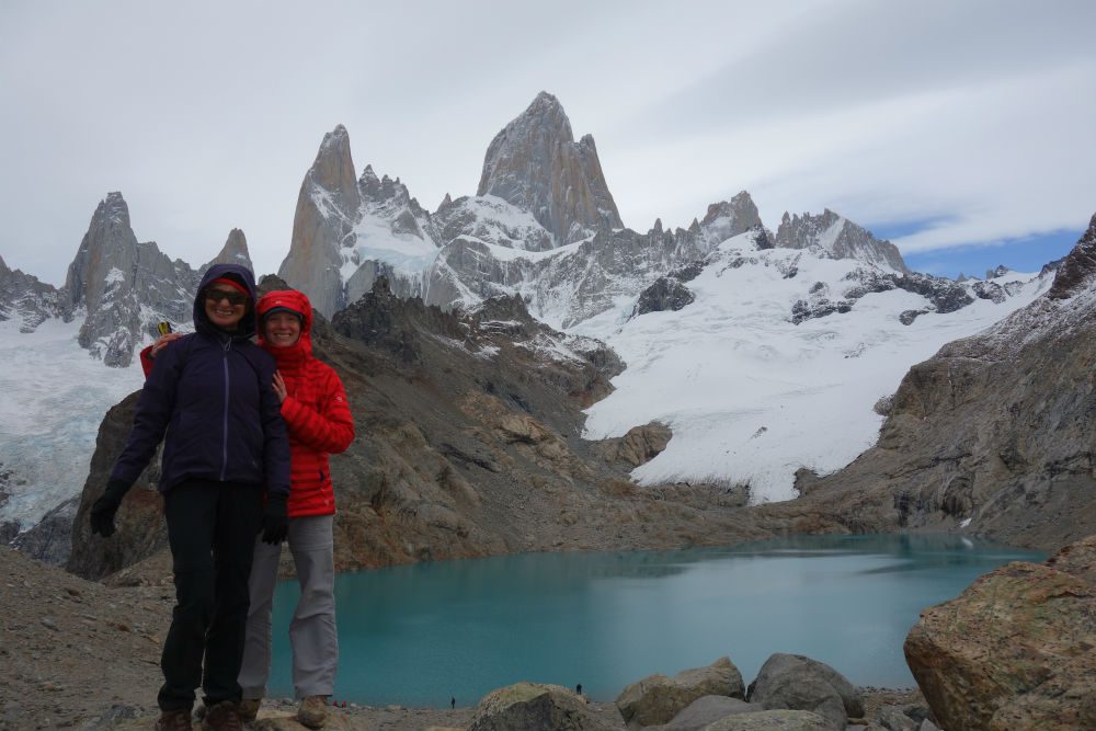 hikers by a turquoise lake and snowy peaks in Patagonia