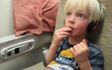 kid eating pretzels and watching TV on a plane