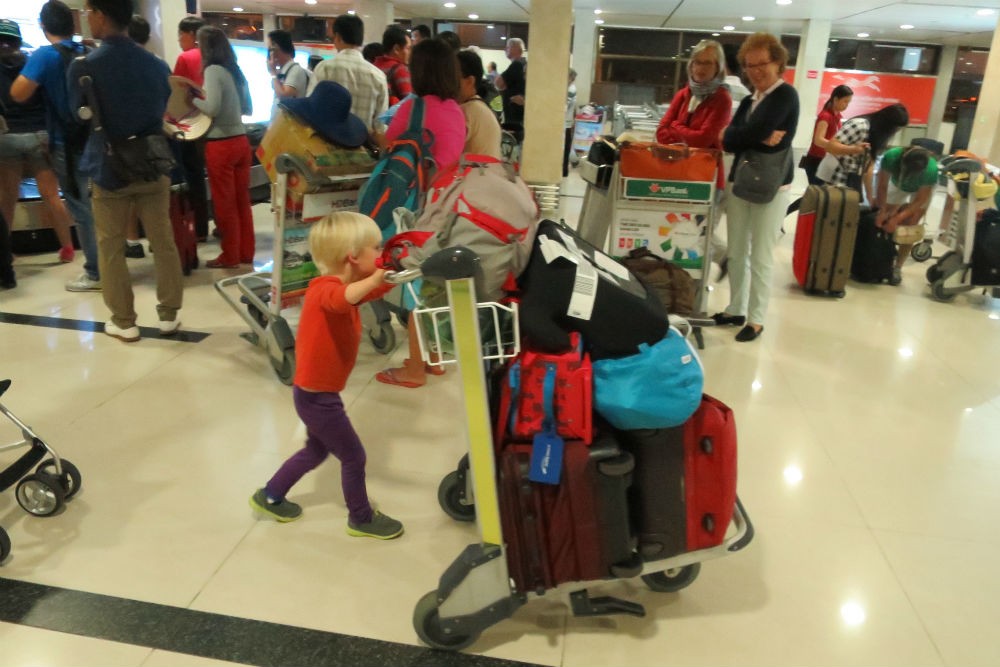 kid in airport pushing luggage cart