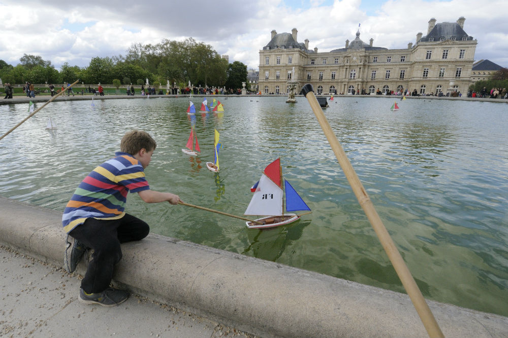 child playing with toy boats in the Jardin du Luxembourg, Paris France