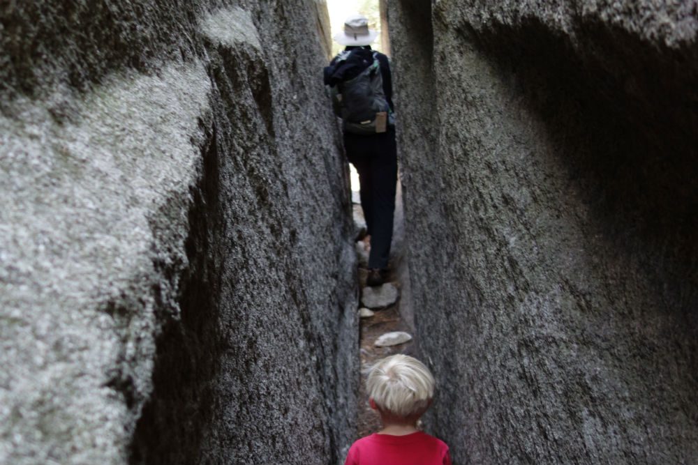 child hiking through a narrow rock crevice in yosemite national park