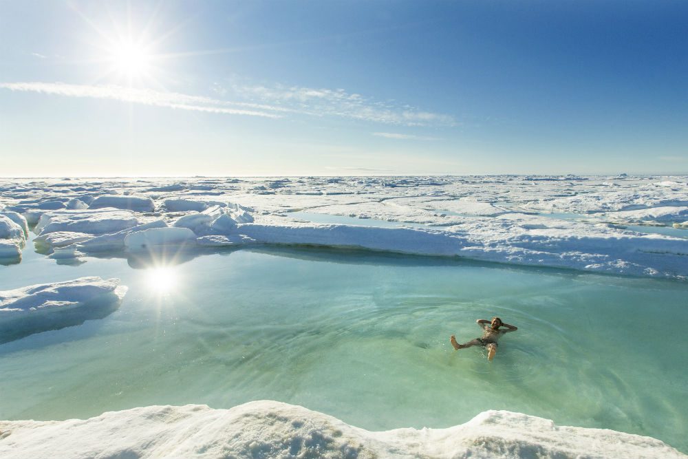 Arctic swimmer floating in snowy lake at Arctic Watch Wilderness Lodge