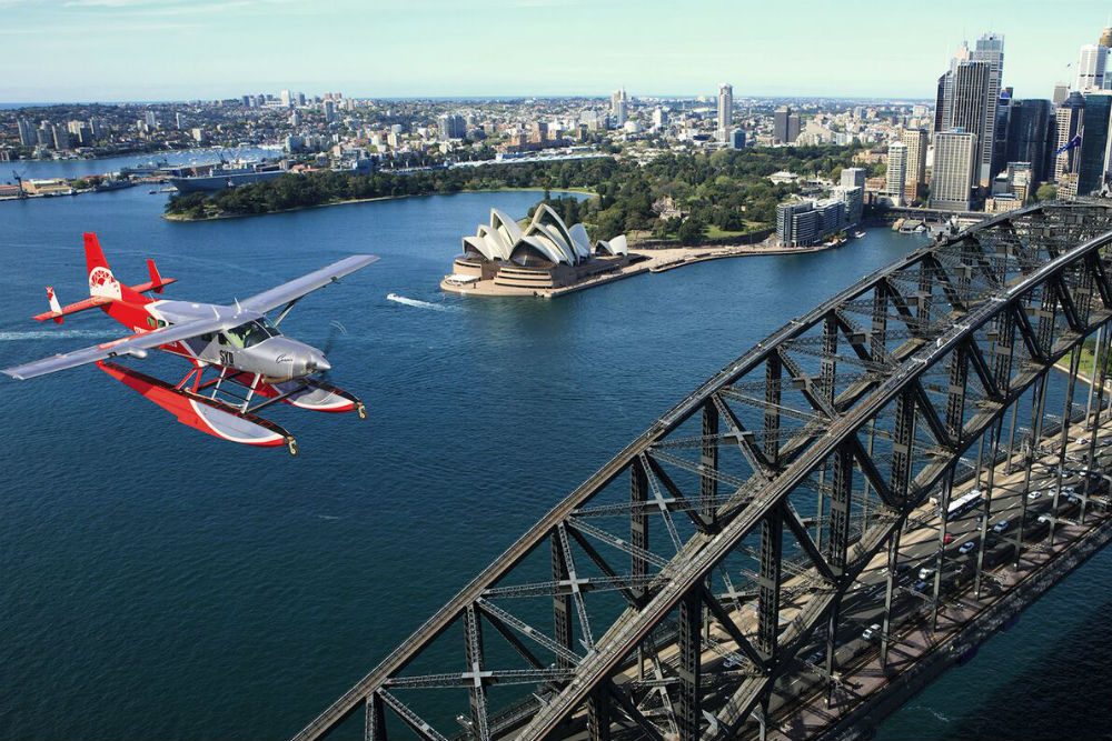 seaplane flying over Sydney Harbour with bridge and opera house