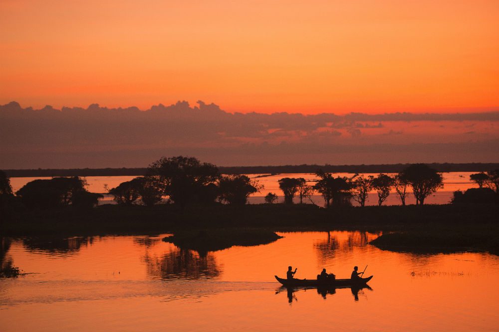 silhouette Sunrise Fisherman fishing on the boat at Tonle Sap lake Cambodia