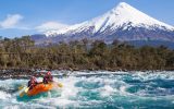 a rafting tour boat on the Petrohue River of Chile with snowcapped mountains in background