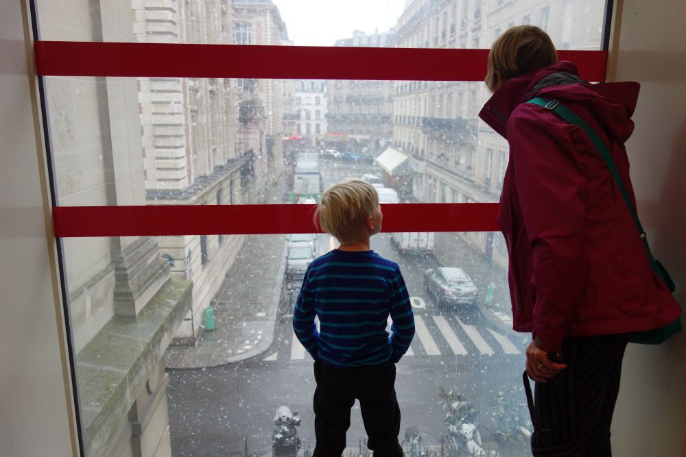 child and adult look out the window at the rain at the Musée des Arts et Métiers in Paris