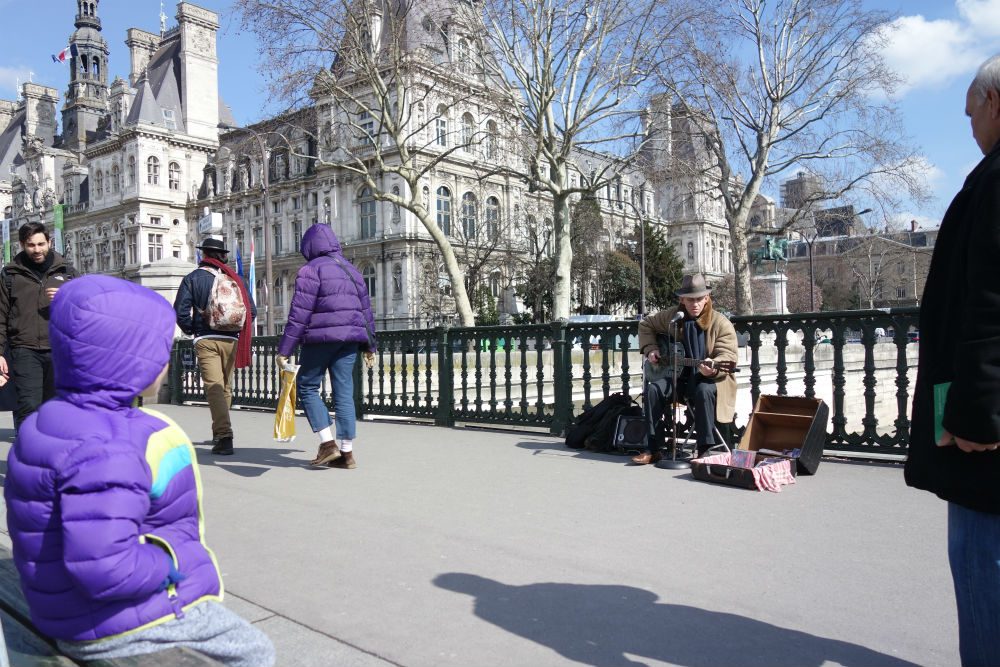 boy stops to listen to a street musician in Paris