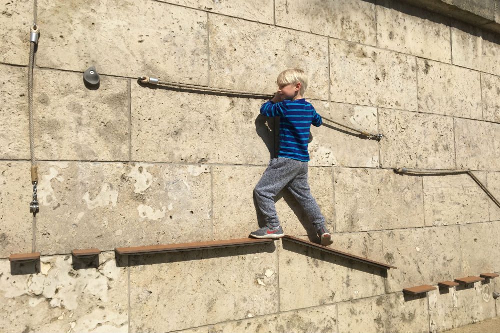 child navigates a via ferrata, one of many children's play places scattered along the banks of the Seine in Paris