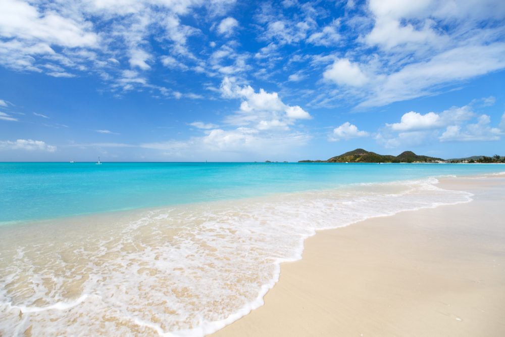Idyllic tropical beach with white sand, turquoise ocean water and blue sky at Antigua island in Caribbean