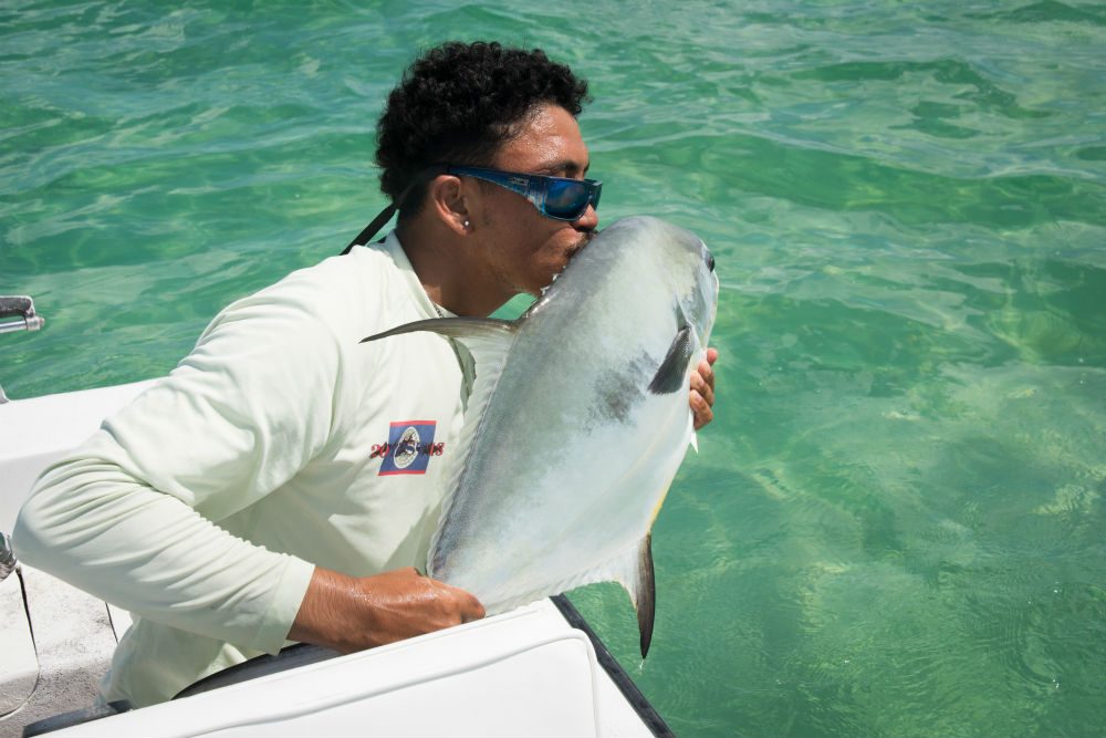 Belize fishing guide kissing fish before putting it back in the water