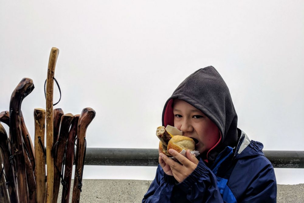 boy eating bratwurst in Bavaria with clouds behind him