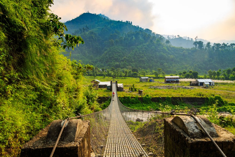 green fields with mountains in background in Chitwan Nepal