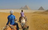 two tourists Riding camels to the pyramids in Egypt