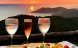 sunset in Costa Rica with two wine glasses and fruit on a table overlooking water and mountains