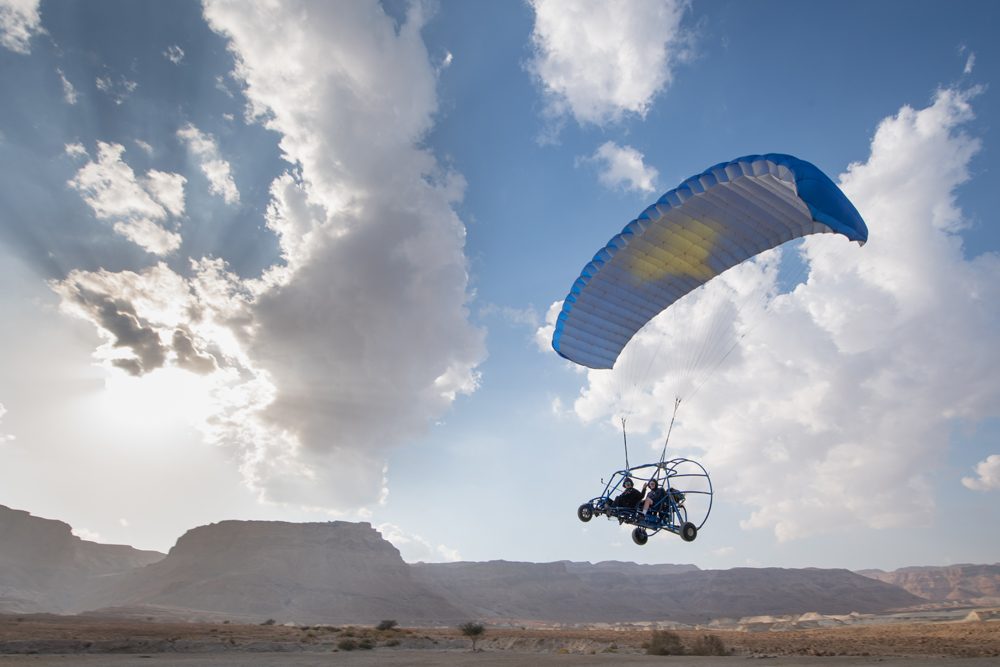 tourists paraglide over Masada Israel