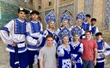 american tourists posing with dancers in traditional blue and white dress in Uzbekistan