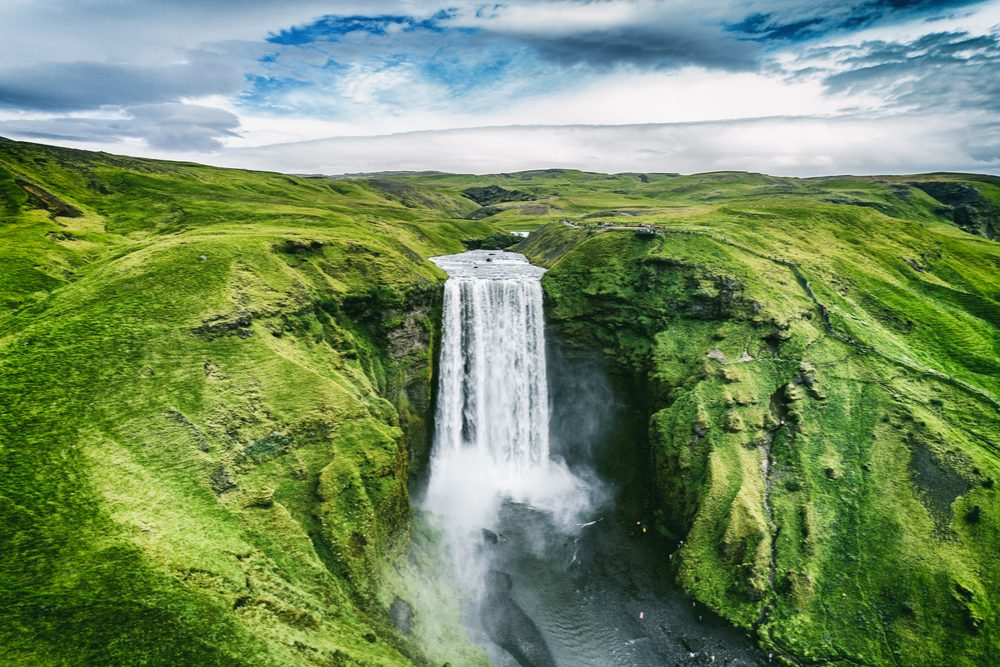 Iceland waterfall Skogafoss in Icelandic nature landscape. Famous tourist attractions and landmarks destination in Icelandic nature landscape on South Iceland. Aerial drone view of top waterfall. -