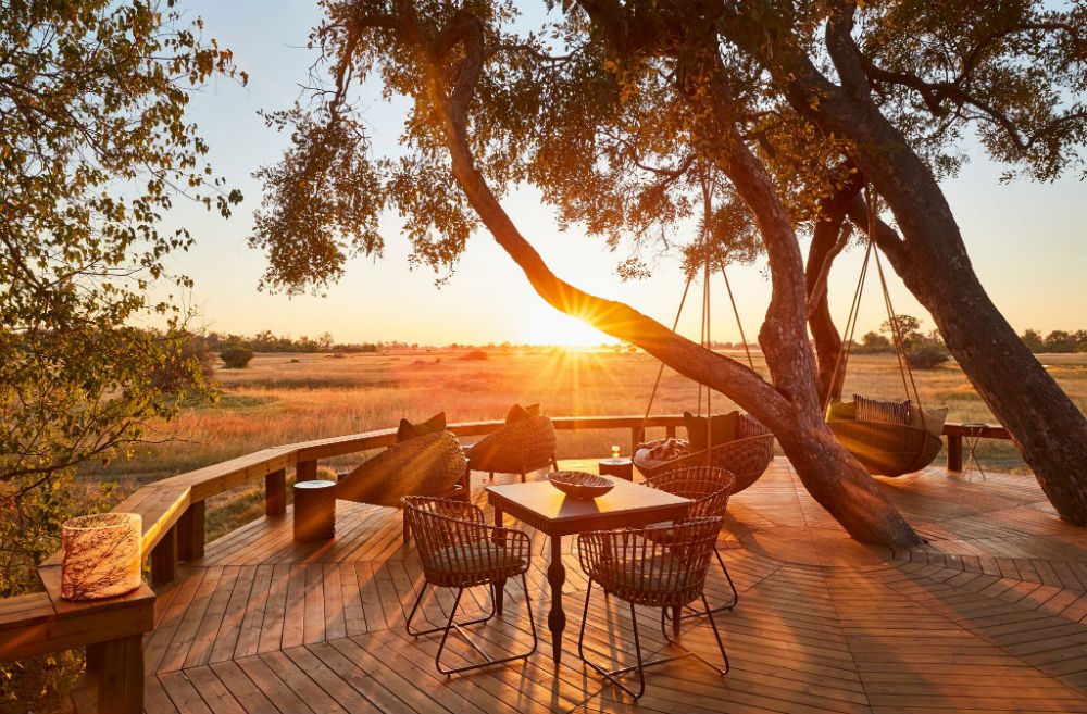 view from the deck of Tuludi safari camp in Botswana with sunset, Okavango delta and tree