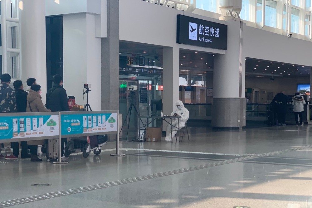 Chengdu Airport on January 30 with masked, fully suited person waiting to do screenings of travelers in line