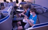 Two teenage boys with masks on in business class of a United airplane during coronavirus
