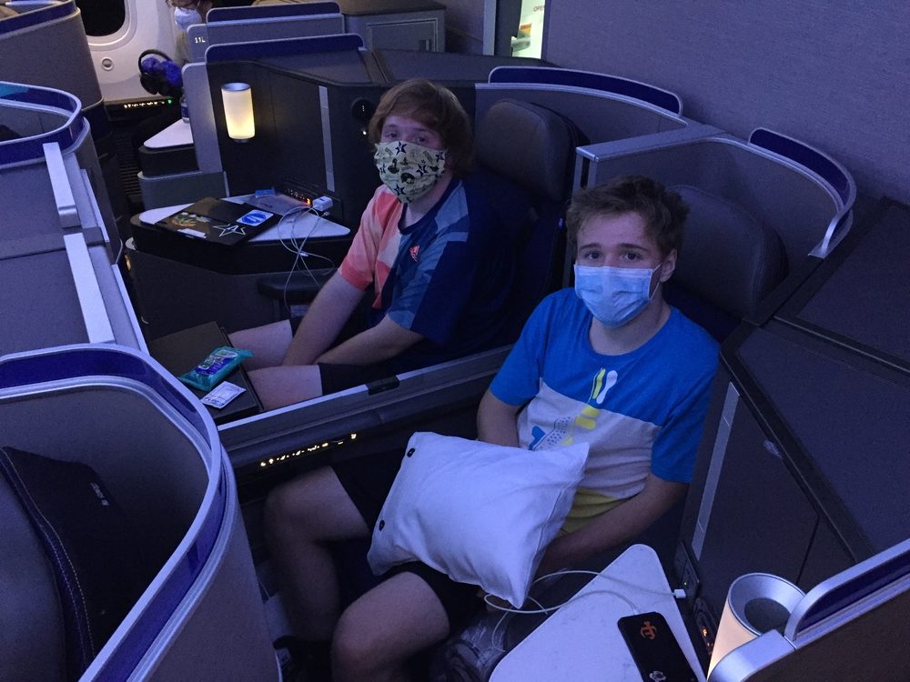 teenage boys traveling in business class United flight with masks on