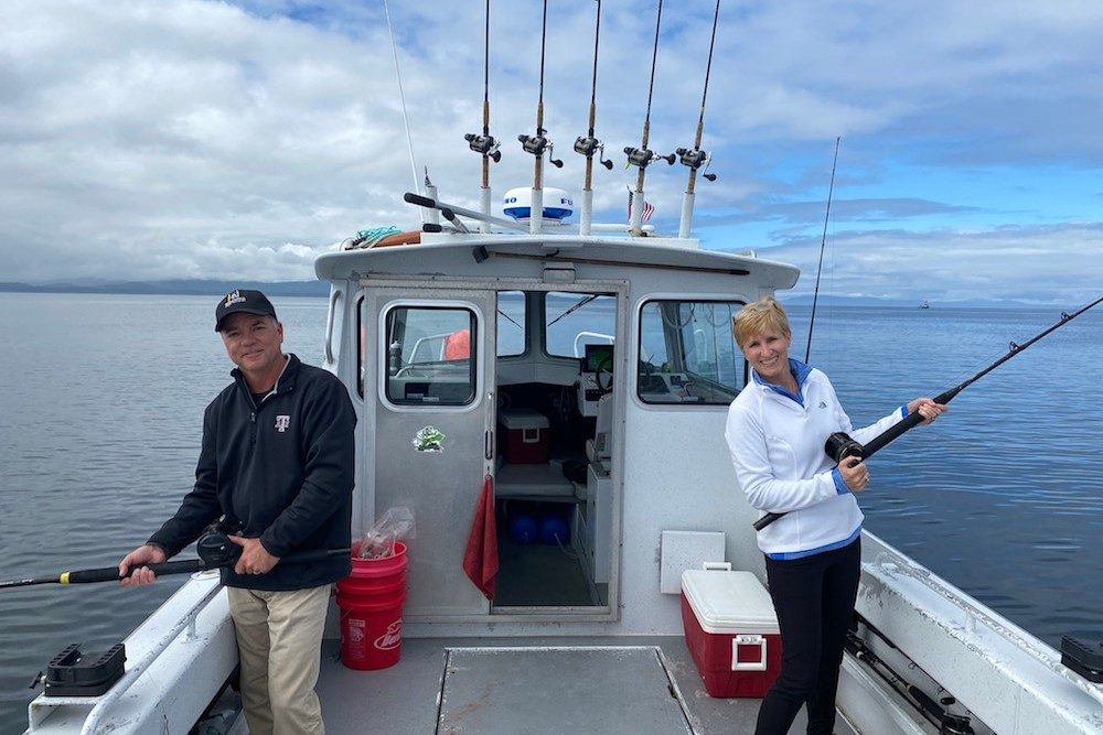 couple fishing off back of boat in Alaska