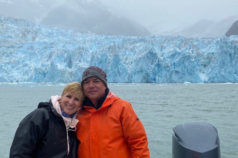 couple posing on a boat in front of a glacier in Alaska