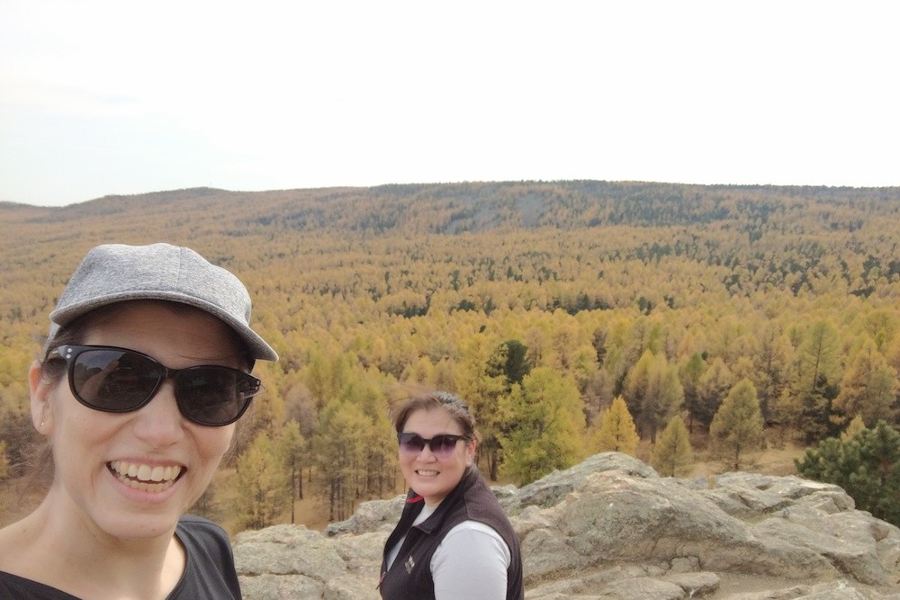 2 women on the mountainop at Tuvhken Monastery overlooking forest in Mongolia