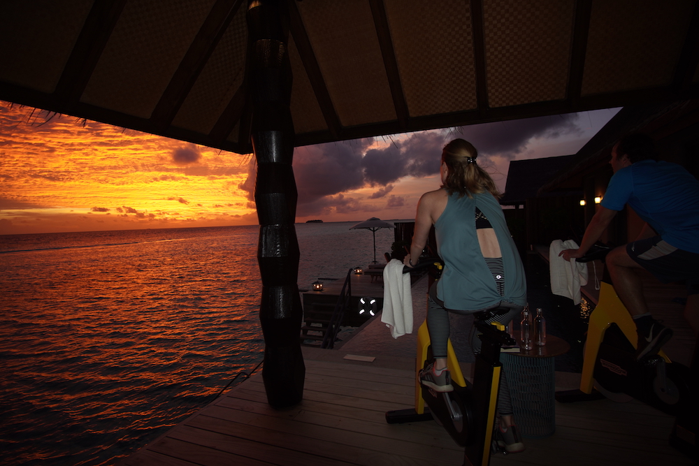 couple on exercise bikes at private overwaterbungalow at JOALI resort in maldives