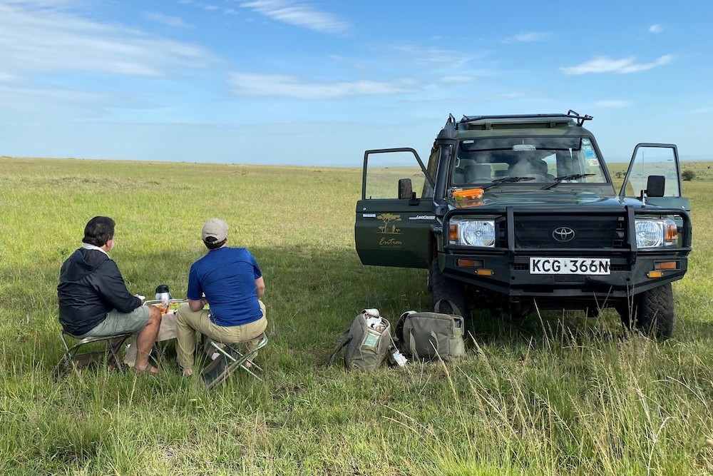 two travelers next to jeep in empty Kenya Mara plain