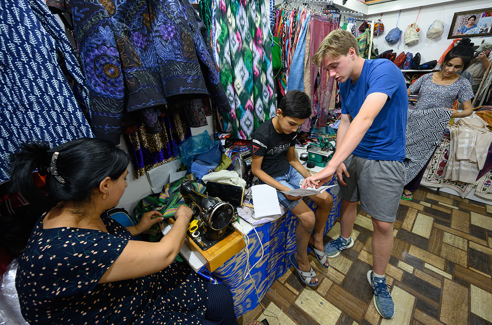 Teenage boy helping young Uzbeki boy with homework in clothing shop