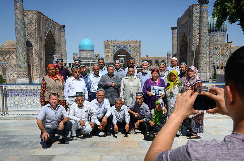 Local Uzbek tourists pose in front of the Registan in Samarkand Uzbekistan