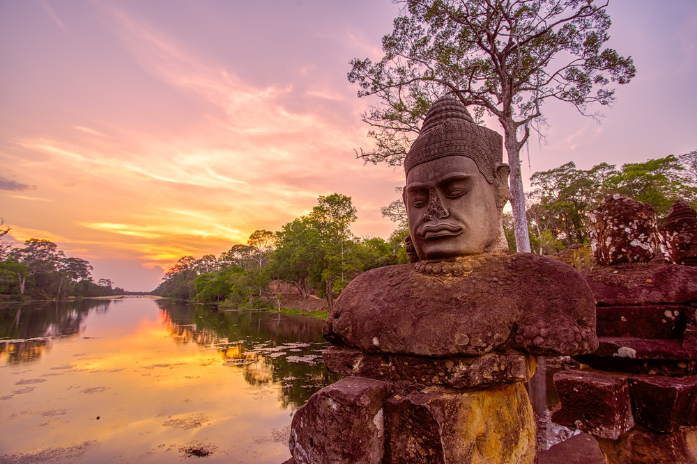 Ancient statues outside South Gate of Angkor Thom at sunset in Siem Reap, Cambodia