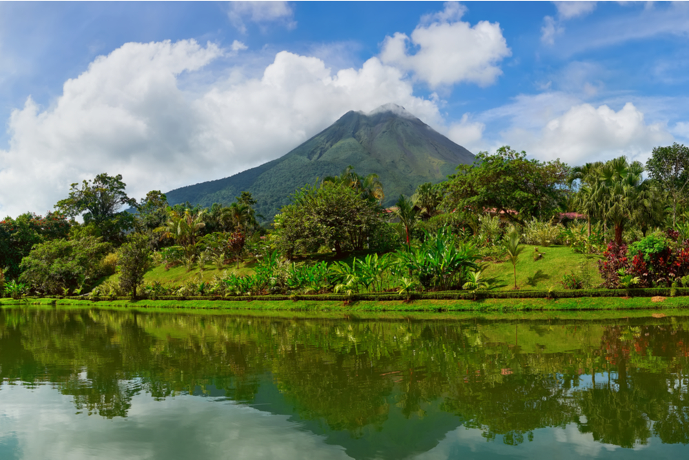 Amazing panoramic view of beautiful nature of Costa Rica with smoking volcano Arenal background. Panorama of volcano Arenal reflected on wonderful picturesque lake, La Fortuna, Costa Rica