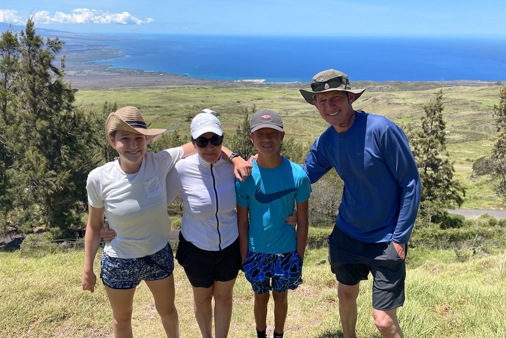 family posing at Pololu Valley with cliffs and ocean in background Big Island Hawaii