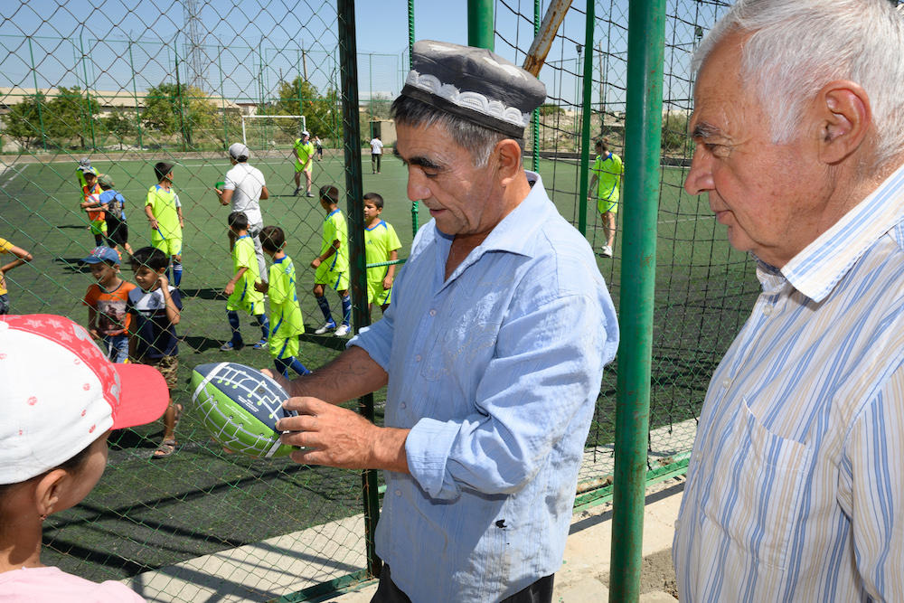 an Uzbek man and child play with a football given to them by an American teenage traveler