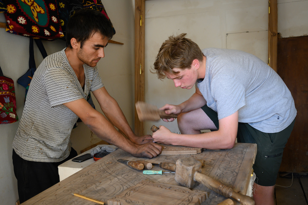 American teenage boy traveler gets ddrum making lesson from local craftsman in Khiva Uzbekistan