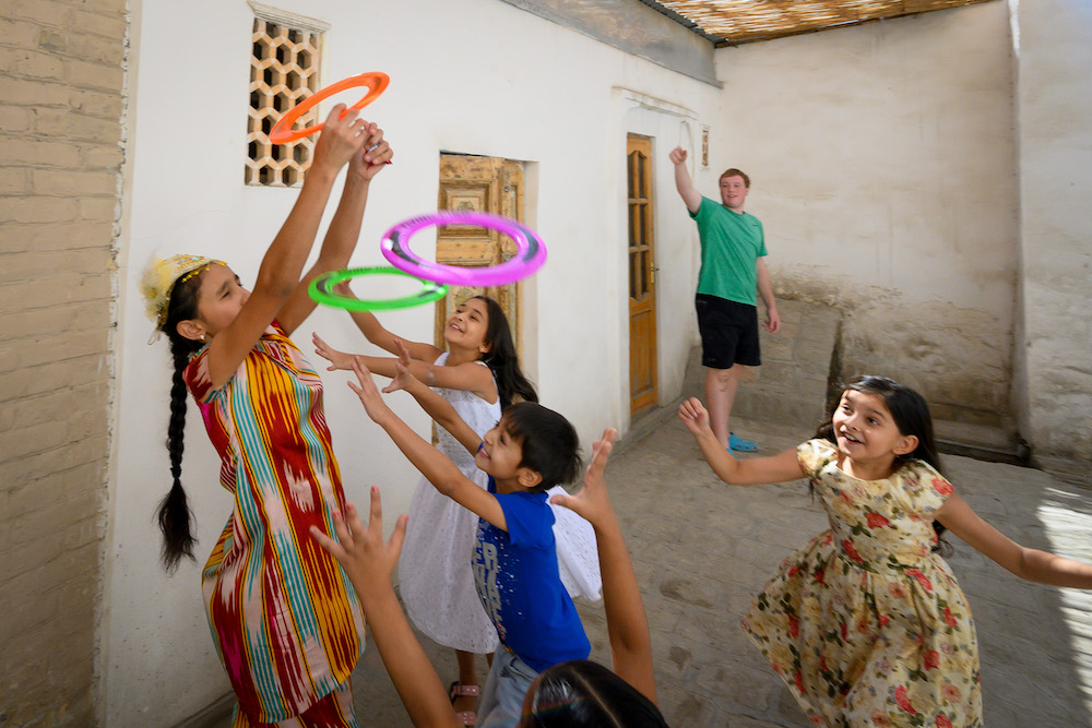 american teenagers and Uzbek children playing with flying rings in Uzbekistan