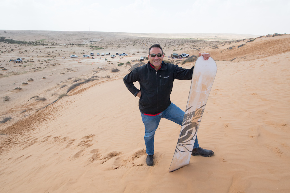 man holding a sandboard in Negev desert Israel