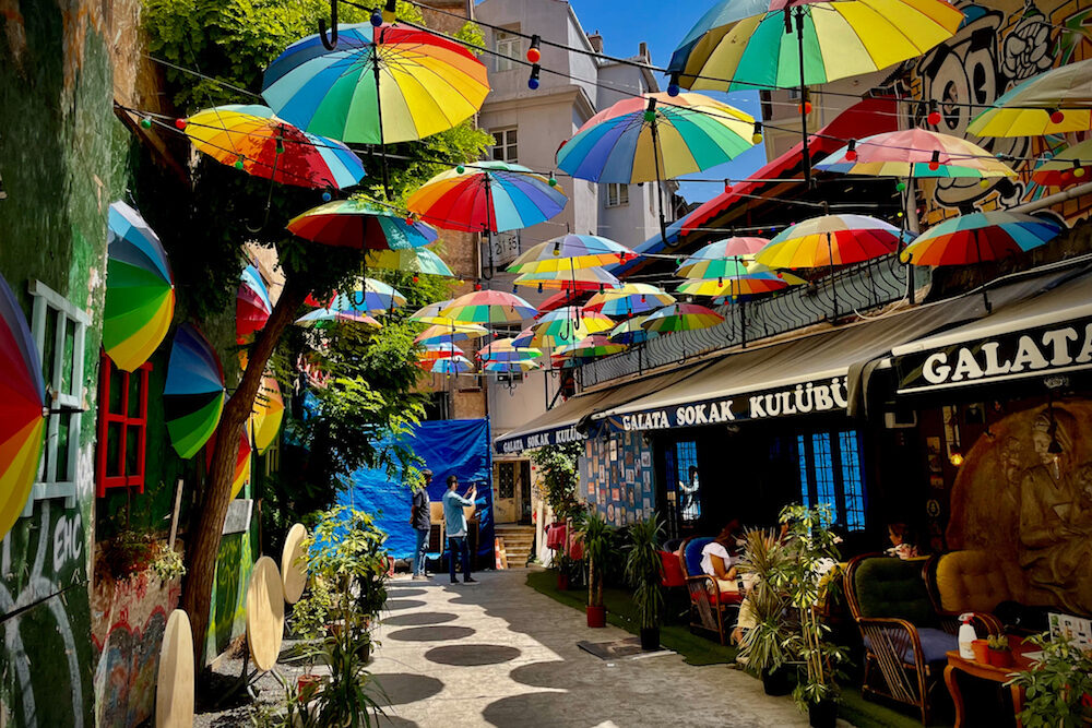 rainbow umbrellas hover over a street of shops and restaurants in Istanbul turkey