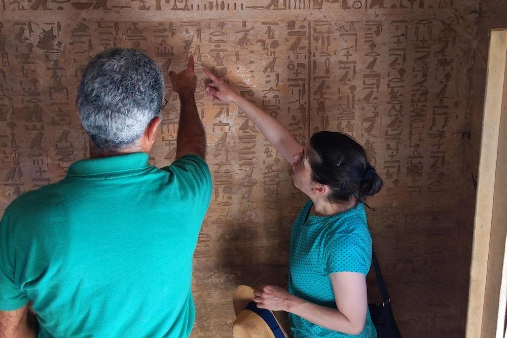 tour guide teaching traveler to read hieroglyphs in Setau's tomb in El Kab Egypt