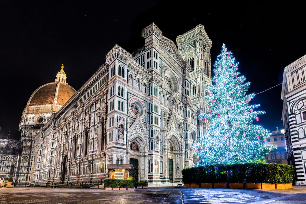 A lit Christmas tree at night in front of Santa Maria del Fiore Florence Italy