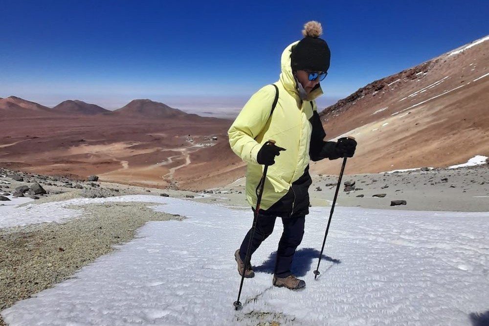 Traveler walking up snowy incline with walking poles in Atacama desert Chile.