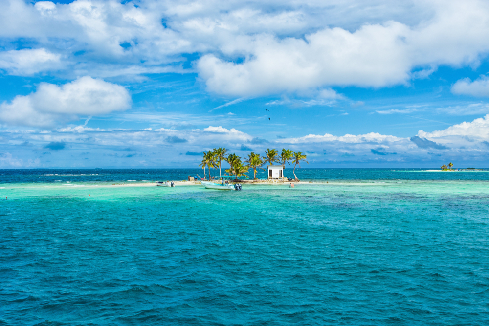 Tiny island with coconut trees and boat in Belize