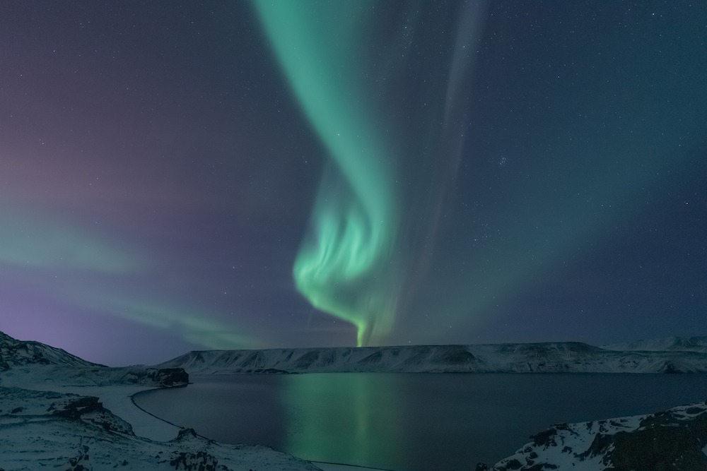 northern lights over snowy flat plateau and lake in iceland